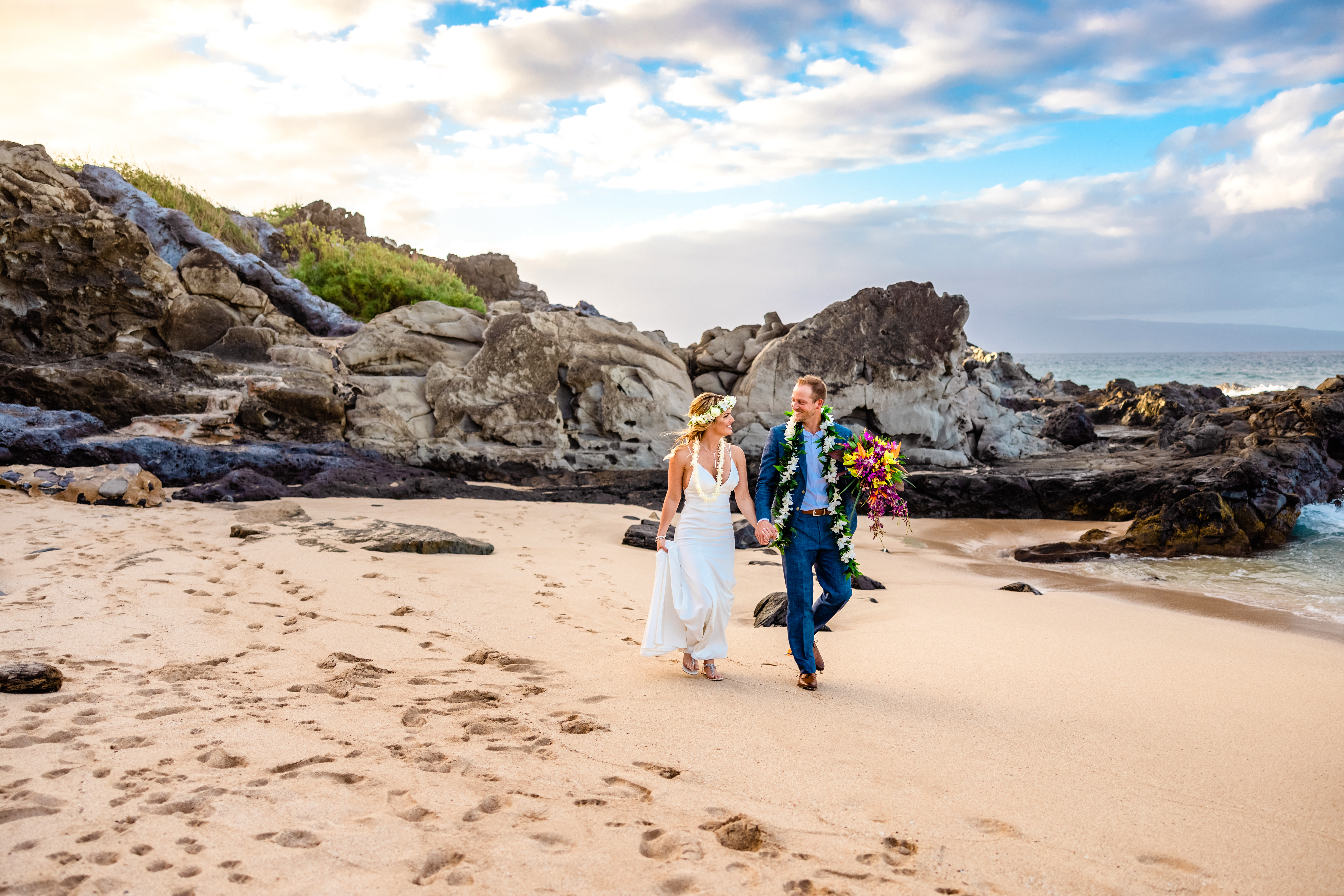 Couple walking on a white sand beach after their Hawaii elopement.