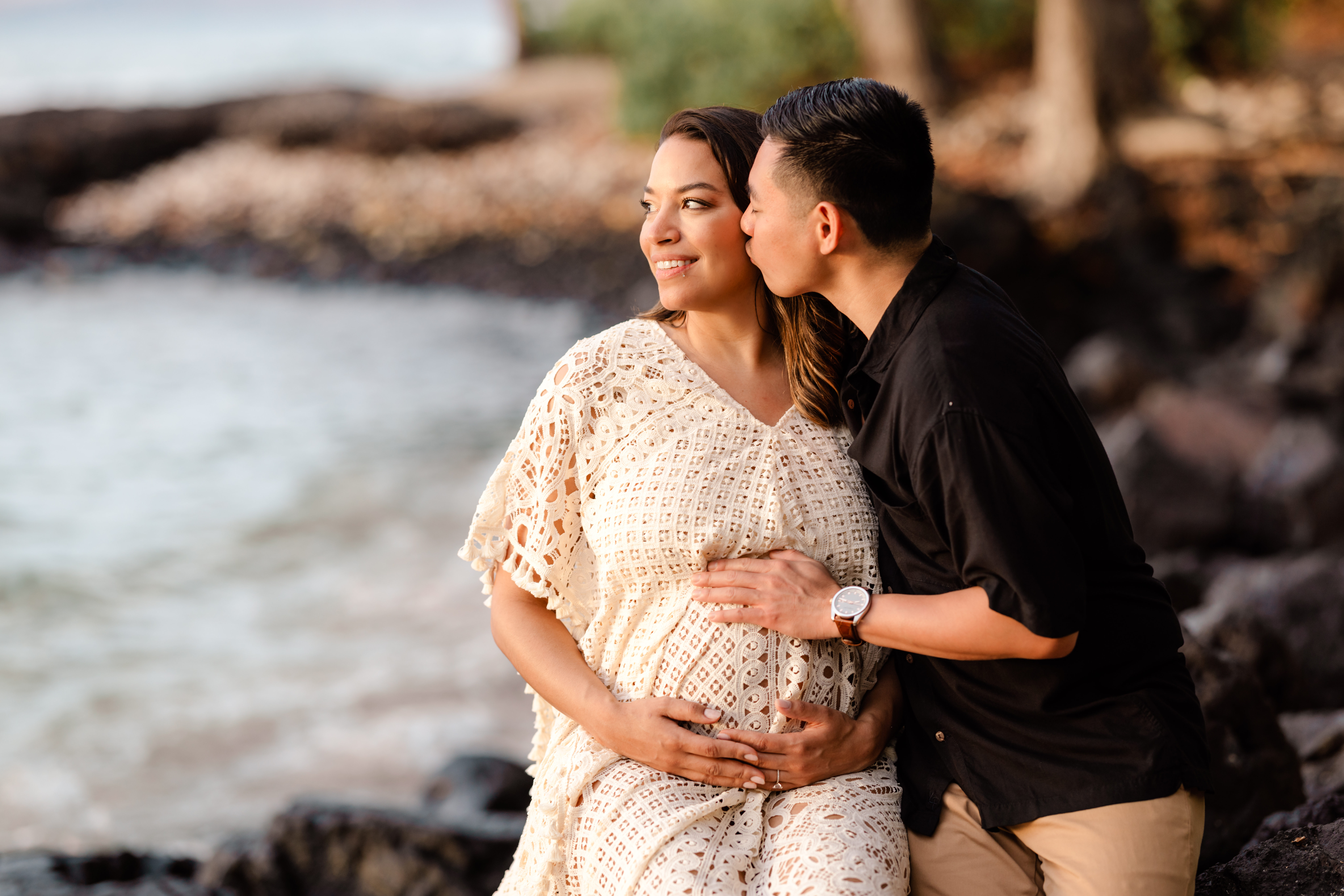 Couple taking maternity photos in Kona Hawaii, black sand beach at sunset