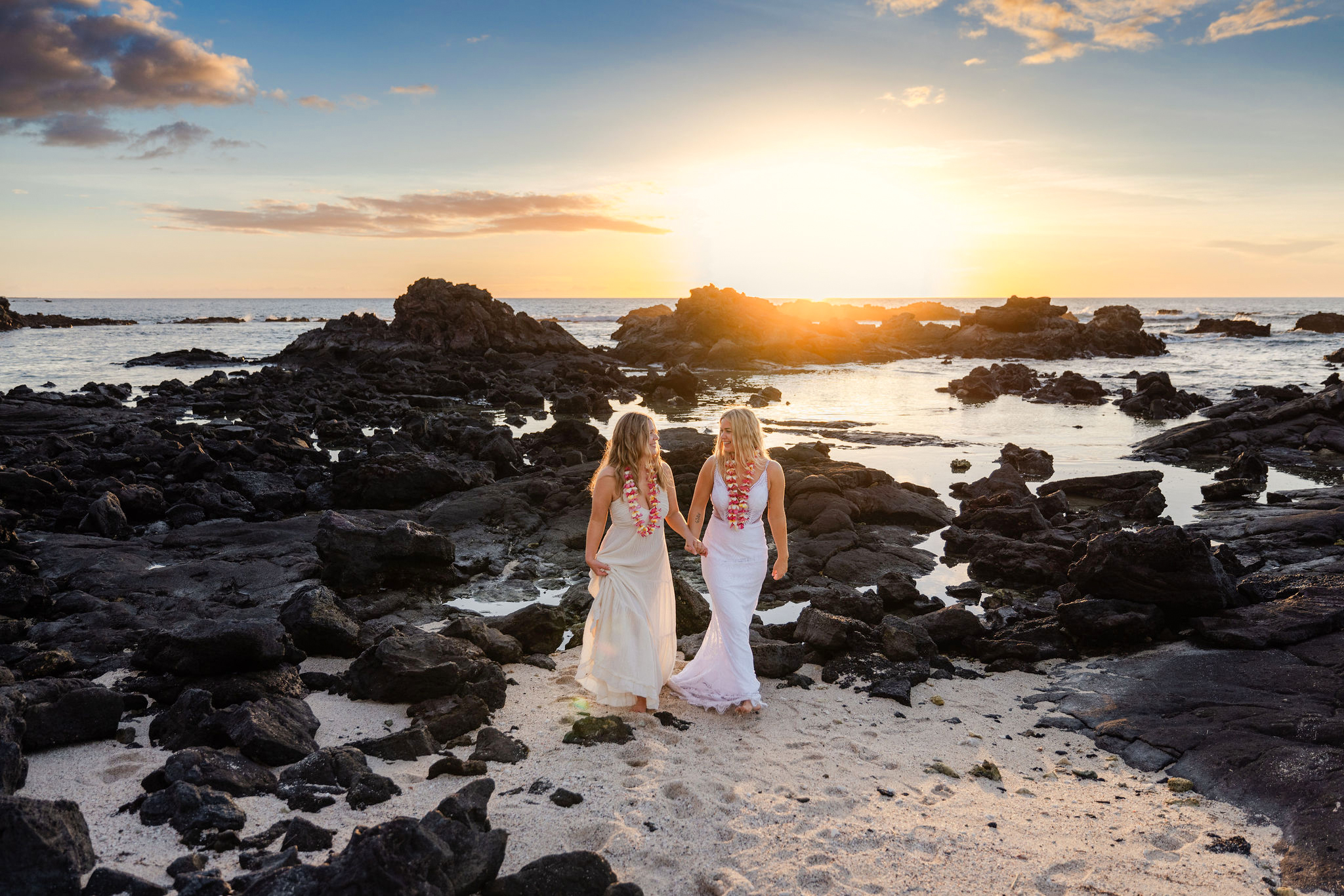 Two beautiful brides walking on lava at sunset following their Big Island elopment in Hawaii